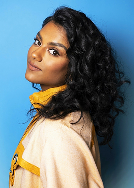 simone ashley in yellow jacket against blue background