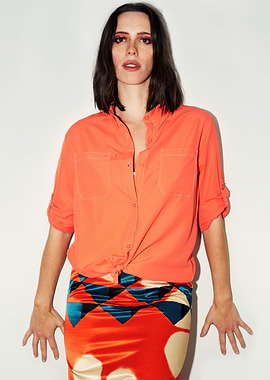 Rebecca Hall in orange shirt and patterned skirt