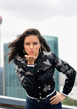 Adriana Lima blowing a kiss in a bomber jacket