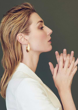 Elizabeth Debicki in white jacket with gold earrings