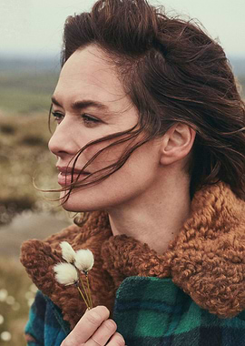 Lena Headey in plaid coat holding cotton flowers