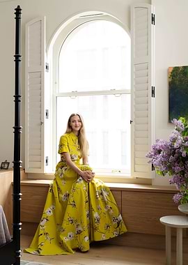 Woman in yellow floral dress by window