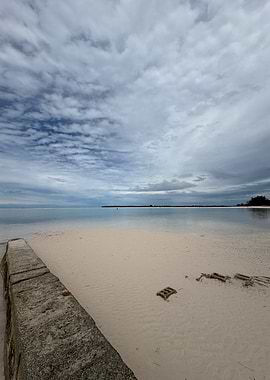 Beach with Calm Water and Cloudy Sky