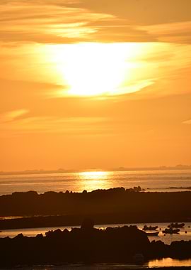 Sunset over rocky coast with boats