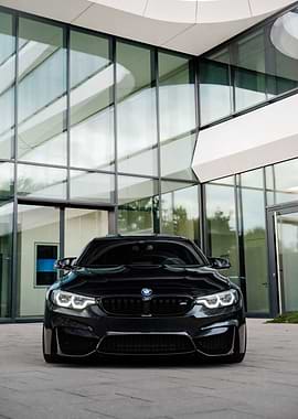 Black BMW M4 in front of modern building