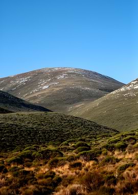 Snow-dusted hills under a clear blue sky