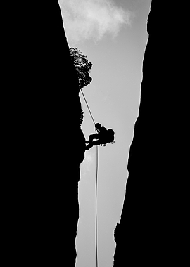 Silhouette of a rappeller descending a canyon