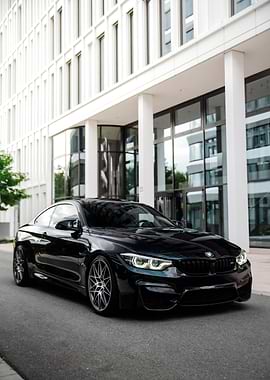 Black BMW M4 Coupe in front of modern building