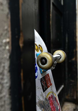 Skateboard with stickers leaning against a door