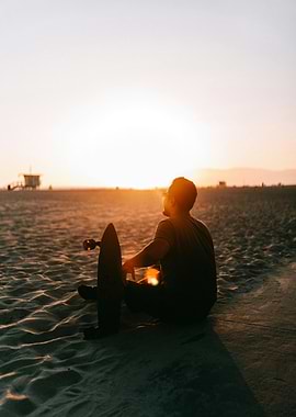 Man with Skateboard Watching Sunset on Beach