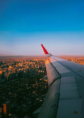 Airplane wing over city at sunset