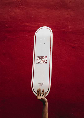 Skateboard held against red wall