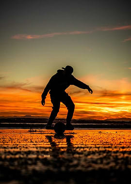 Silhouette of a person playing soccer at sunset