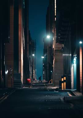 Man walking down a dark city alley at night