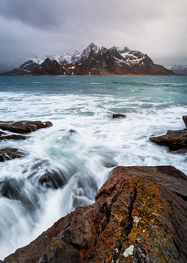 Waves crashing on rocky shore with mountains