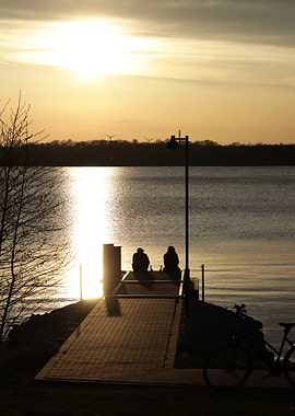 Couple sitting on pier at sunset