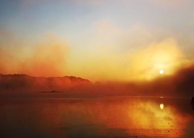 The sun rises through mist over a lake in the Appalachi ...
