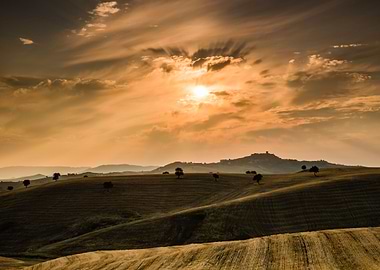 Wheat fields hills at sunrise with historic village of ...