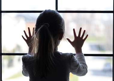 Young girl at window (in partial silhouette) hands pres ...