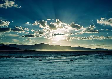The sun sets behind the mountains in the desert.