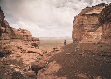 A man stands thoughtfully on a bluff looking over the d ...
