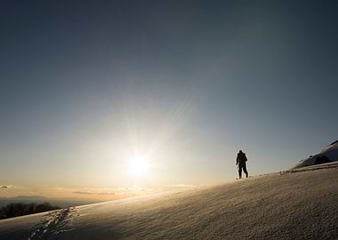 The sunsets behind the shadow of a backcountry skier.