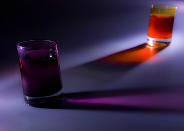 Two shot glasses with orange and purple liquids in them ...
