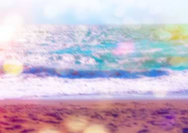 sandy beach with blue wave and summer light bokeh