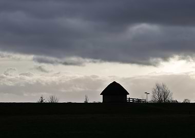 Silhouetted Cottage Under Cloudy Sky