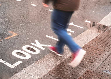 London, England I Pedestrian in motion on a crossing with Look Left inscription on the ground under the rain in the urban dynamic of a London street with a retro vintage autumn aesthetic