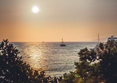 Sunset over the ocean with sailboats