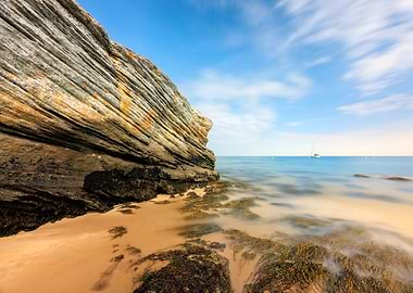 Coastal Rock Formation with Distant Sailboat
