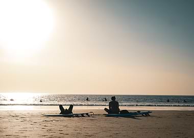 Surfers Relaxing on Beach at Sunset