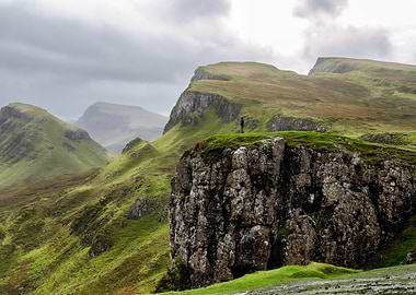 Person on Cliff Overlooking Green Hills