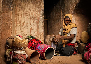 African man with drums in earthen room