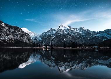 snowy mountains reflected in lake at night