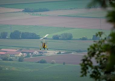 Yellow Autogyro Flying Over Green Fields