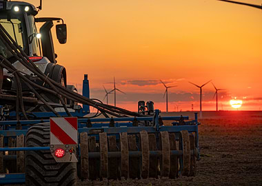 Tractor and Wind Turbines at Sunset