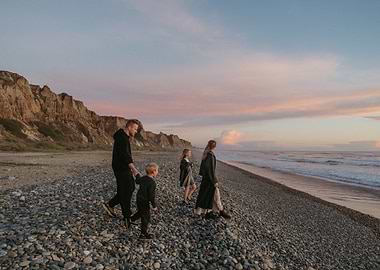 Family walking on pebble beach at sunset