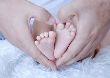 Baby feet in heart-shaped hands