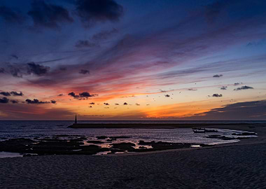 Sunset over the ocean with lighthouse