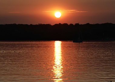 Sunset over water with boat silhouette