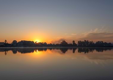 Sunrise over calm water reflection