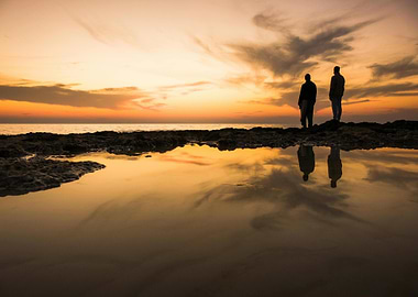 Two figures at sunset by the sea