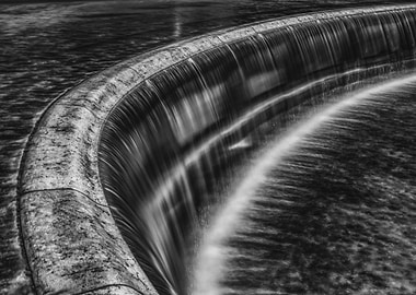 Monochrome Waterfall Over Curved Dam