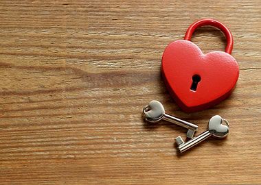 Heart-shaped padlock with keys on wood