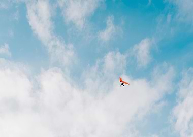 Hang glider soars in cloudy sky