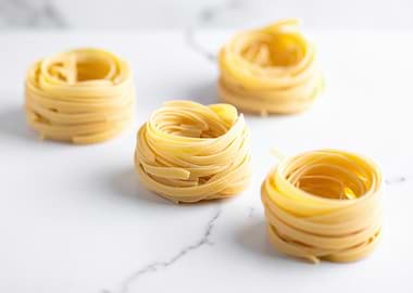 Four Tagliatelle Nests on Marble Surface