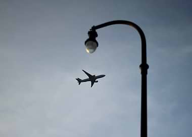 Airplane flying near a street lamp