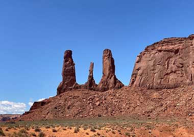 Monument Valley Three Sisters rock formations under blue sky